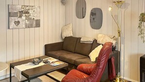 A living room with a brown sofa, a red leather chair, a coffee table, and a floor lamp. - 4 Person Holiday Home in Skulestadmo (Voss)
