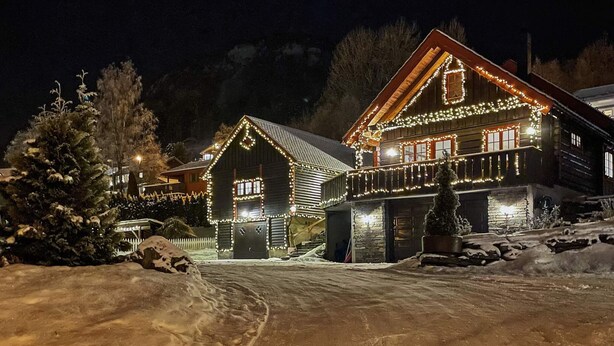 A wooden cabin with a sloped roof, surrounded by snow, and decorated with string lights. - 4 Person Holiday Home in Skulestadmo (Voss)