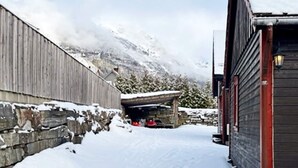 A narrow snow-covered alleyway flanked by wooden buildings, leading to a stone structure with a red roof. - 4 Person Holiday Home in Skulestadmo (Voss)