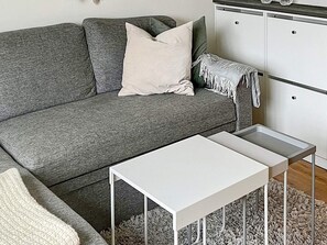 A grey sofa with a white pillow and a white side table in a room with a white cabinet and a grey shag rug. - 5 Person Holiday Home in Salen (Salen)