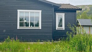 A dark wooden house with two white-framed windows and a small porch area. - 5 Person Holiday Home in Salen (Salen)