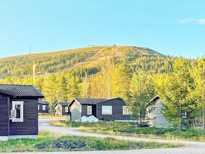 A row of small cabins with a dirt road in front, surrounded by trees and a mountain in the background. - 5 Person Holiday Home in Salen (Salen)