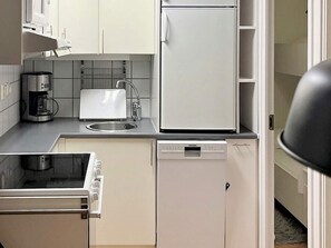 A compact kitchen with a coffee maker, sink, refrigerator, and dishwasher.