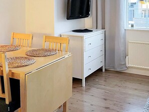 A room with a wooden dining table, chairs, a white dresser, and a television mounted on the wall. - 5 Person Holiday Home in Salen (Salen)