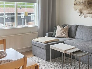 A modern living room with a grey sofa, a small white table, and a window with curtains. - 5 Person Holiday Home in Salen (Salen)