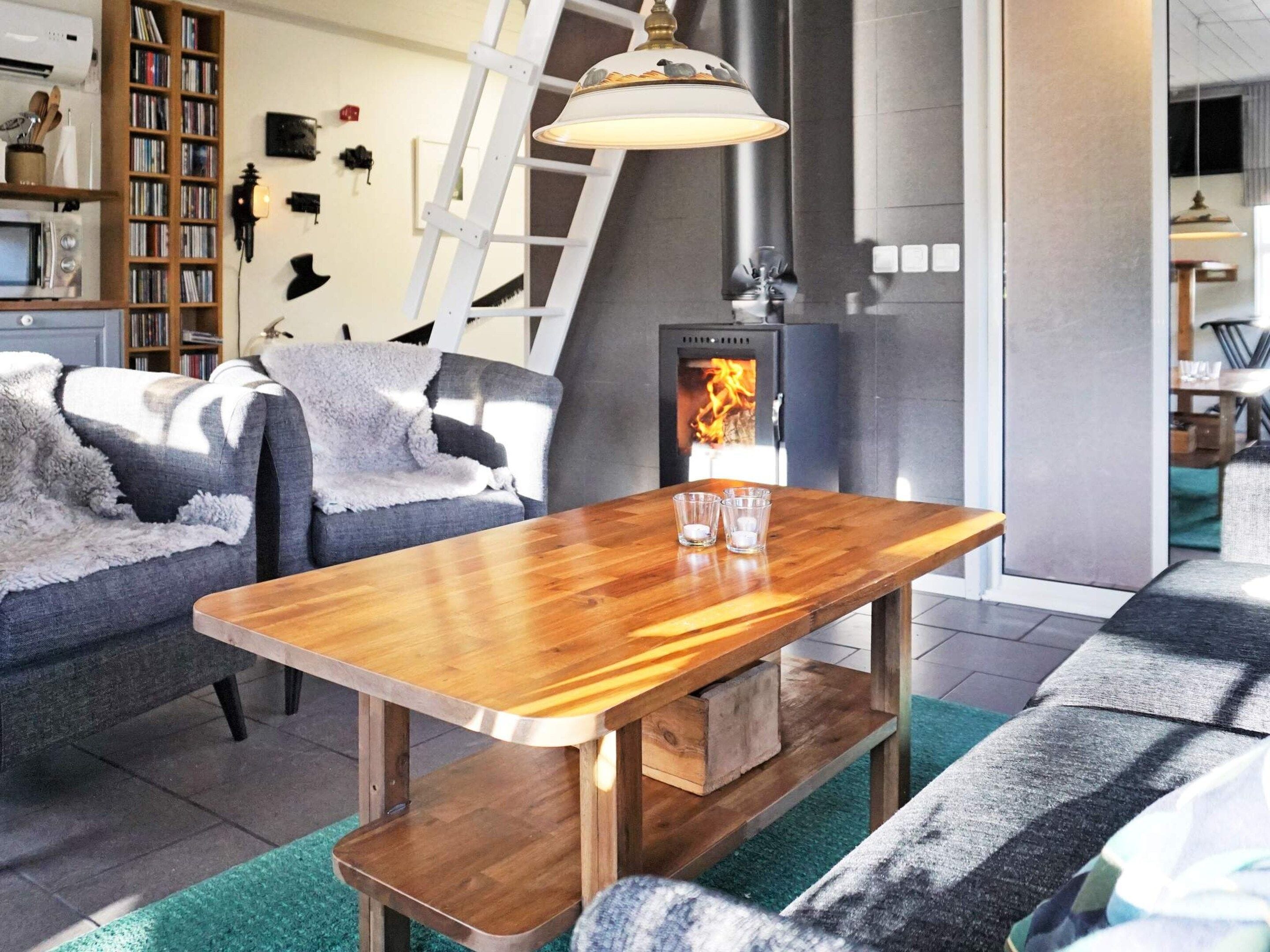 Una sala de estar acogedora con una mesa baja de madera, chimenea, estantería y una escalera.