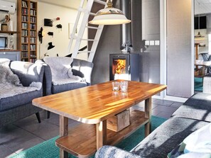 A cozy living room with a wooden coffee table, a fireplace, a bookshelf, and a ladder. - 4 Star Holiday Home in Paryd (Påryd)