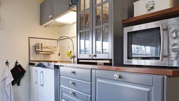 A kitchen with a microwave, cabinets, and a sink.