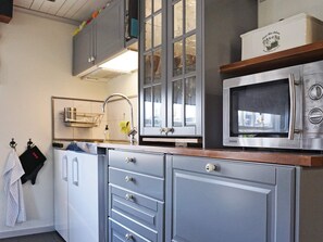 A kitchen with a microwave, cabinets, and a sink. - 4 Star Holiday Home in Paryd (Påryd)