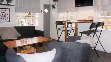 A cozy living room with a sofa, a wooden coffee table, and a dining table with chairs.