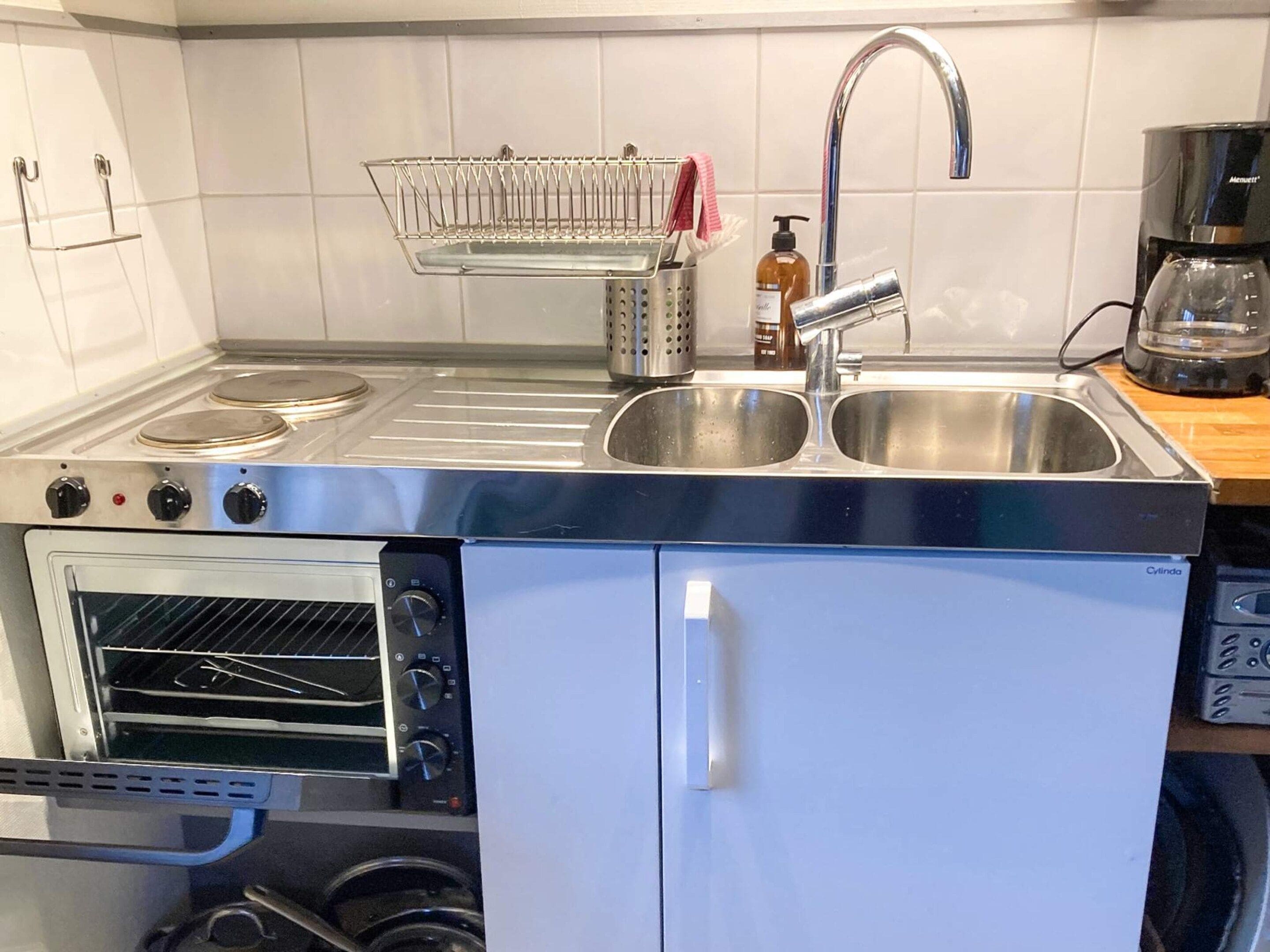 Una cocina compacta con horno empotrado, pileta doble y cafetera.