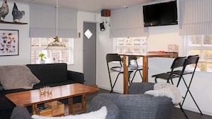 Una sala acogedora con un sofá, una mesa de centro de madera y una mesa de comedor con sillas.