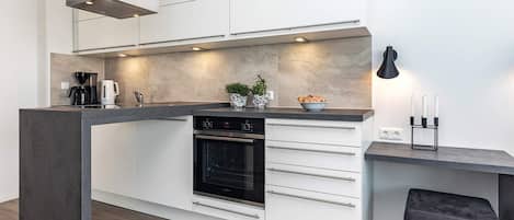 Cozinha moderna com forno embutido, cafeteira e uma pequena planta em vaso.