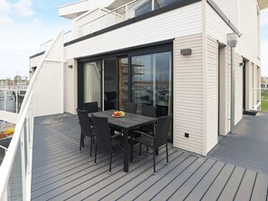 A modern outdoor dining area with a table and chairs, overlooking a marina. - Marina-apartment in Premiumlage (Wendtorf)