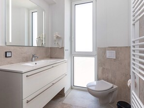 A modern bathroom with a large mirror, a sink, a toilet, and a towel rack. - 5 Star Holiday Home in Wendtorf (Wendtorf)