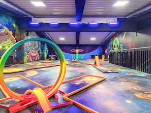 An indoor play area with colorful murals, a large circular structure, and various play equipment.