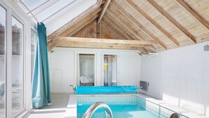 A swimming pool with a glass enclosure, a wooden ceiling, and a view of the outside. - 4 Star Holiday Home in Fjerritslev (Fjerritslev)