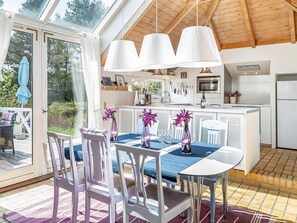 Une cuisine moderne avec des meubles blancs, un îlot central et des luminaires suspendus.