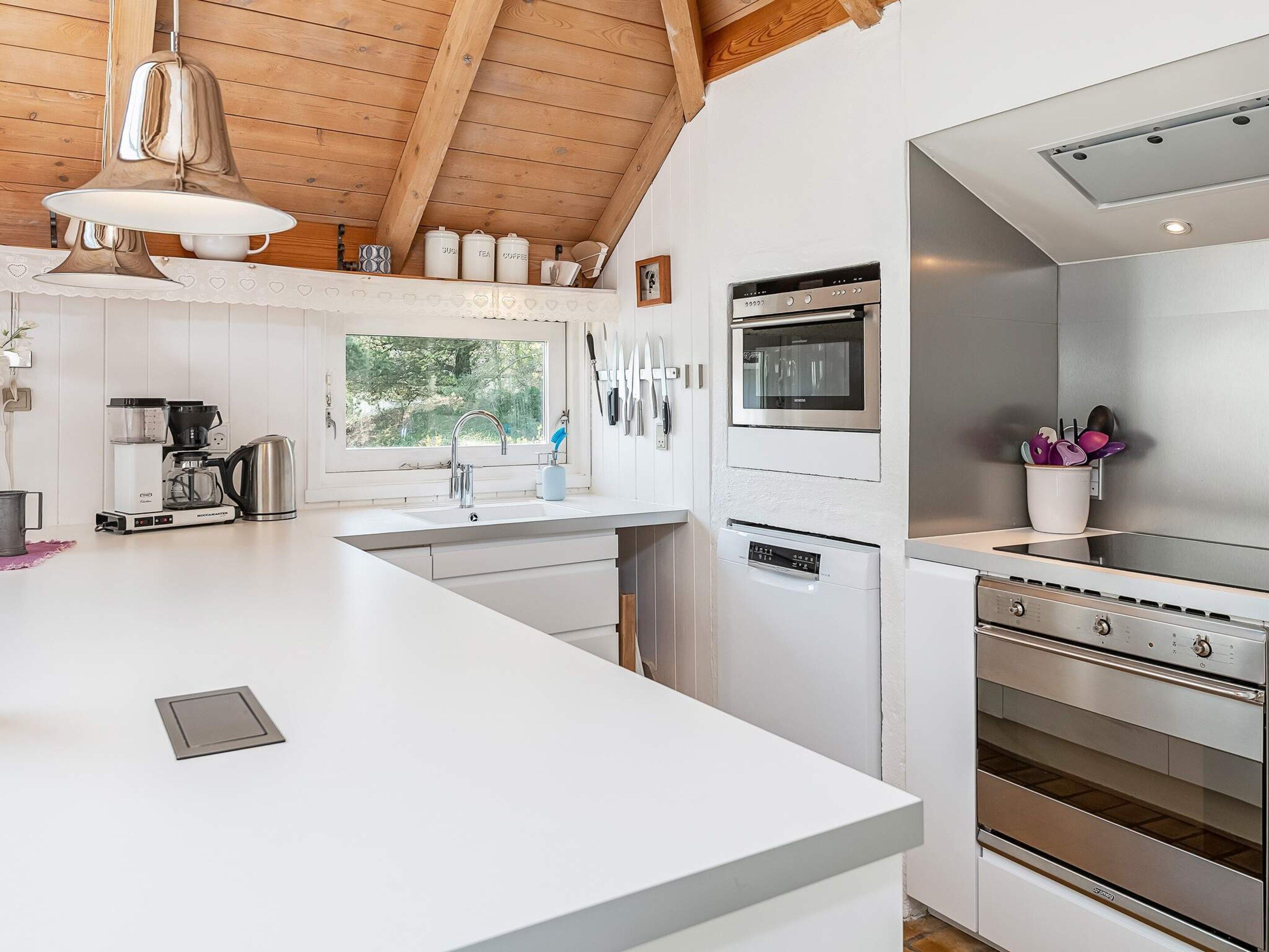 A modern kitchen with a large island, stainless steel appliances, and a window providing natural light.