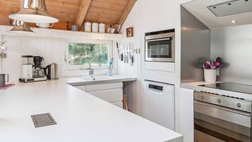 A modern kitchen with a large island, stainless steel appliances, and a window providing natural light.
