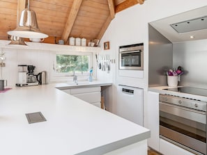A modern kitchen with a large island, stainless steel appliances, and a window providing natural light. - 4 Star Holiday Home in Fjerritslev (Fjerritslev)