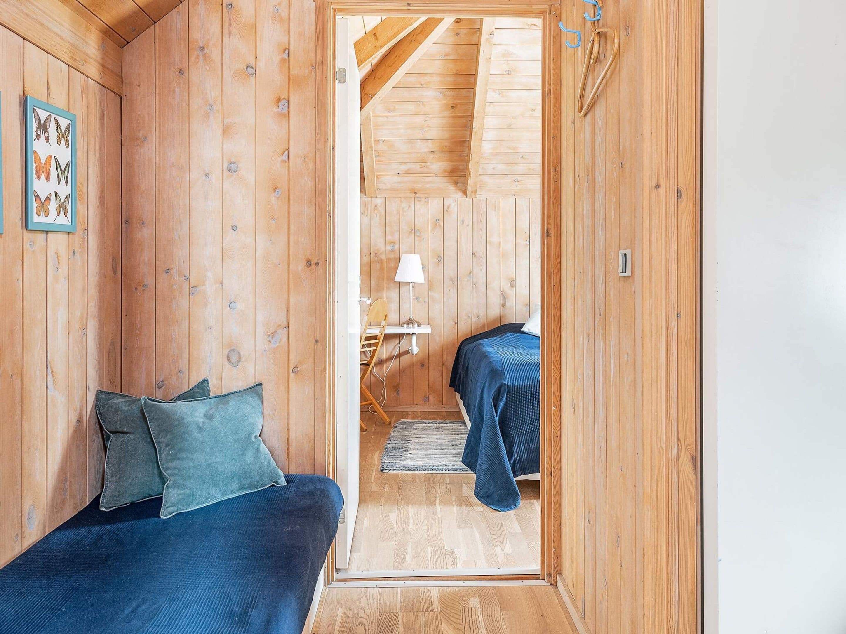 A wooden room with two beds, a desk, and a chair.