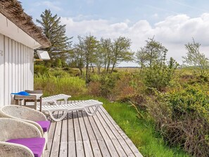 A wooden deck with wicker chairs and a table, overlooking a natural landscape with trees and bushes. - 4 Star Holiday Home in Fjerritslev (Fjerritslev)