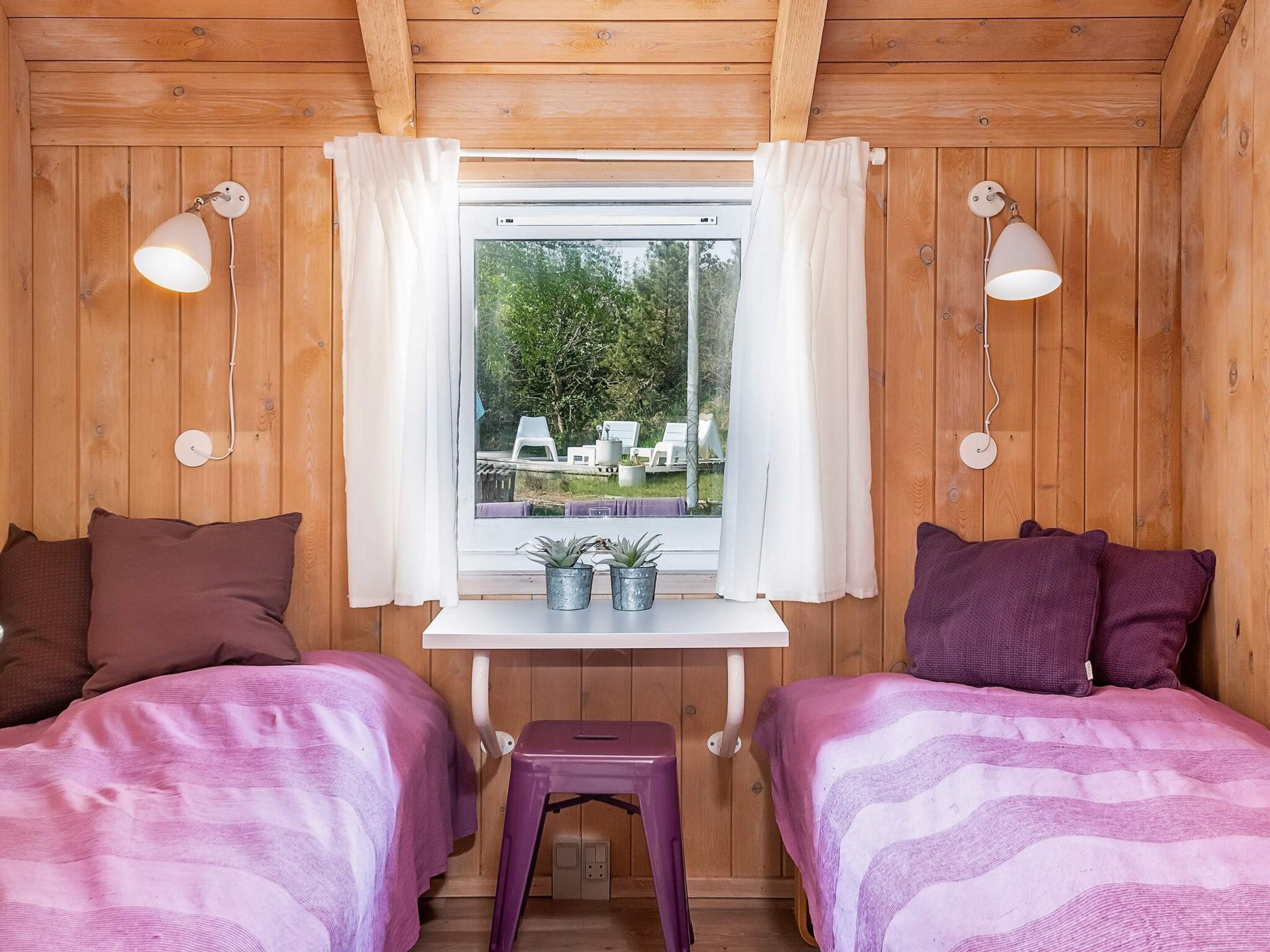 A room with two beds, a small table, and a window with curtains.