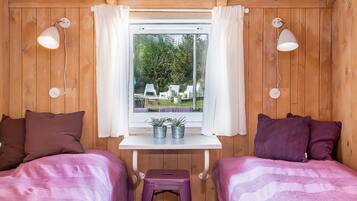 A room with two beds, a small table, and a window with curtains.