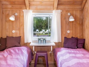 A room with two beds, a small table, and a window with curtains. - 4 Star Holiday Home in Fjerritslev (Fjerritslev)