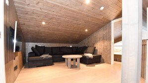 A cozy attic room with a wooden ceiling, a sofa, a small table, and a wooden floor. - 4 Star Holiday Home in Idre (Idre)