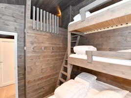 Habitación con literas, paredes de madera y una escalera.