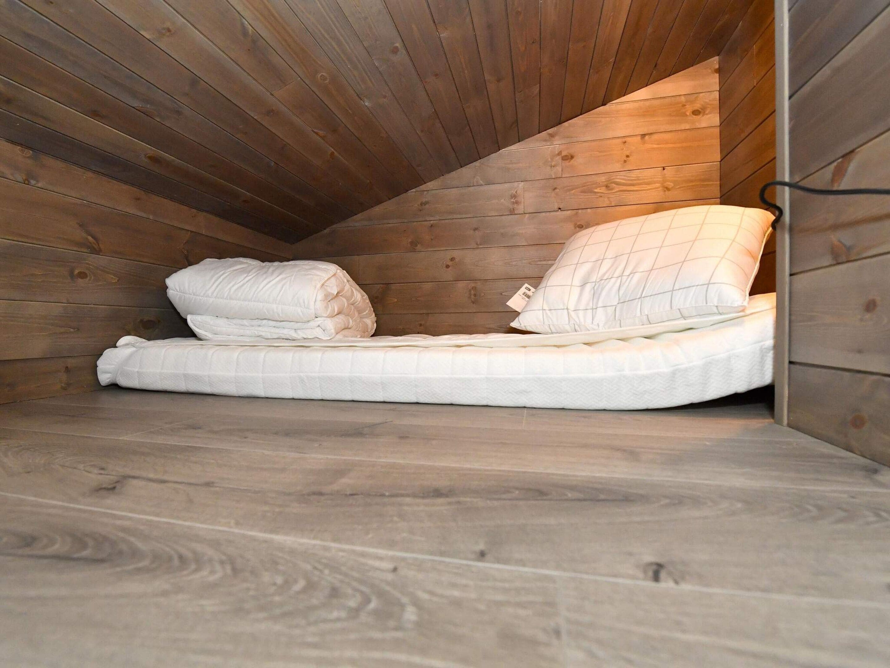 Un lit simple dans une pièce en bois avec des plafonds inclinés.