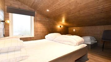 A wooden-paneled room with a bed, a chair, and a window.