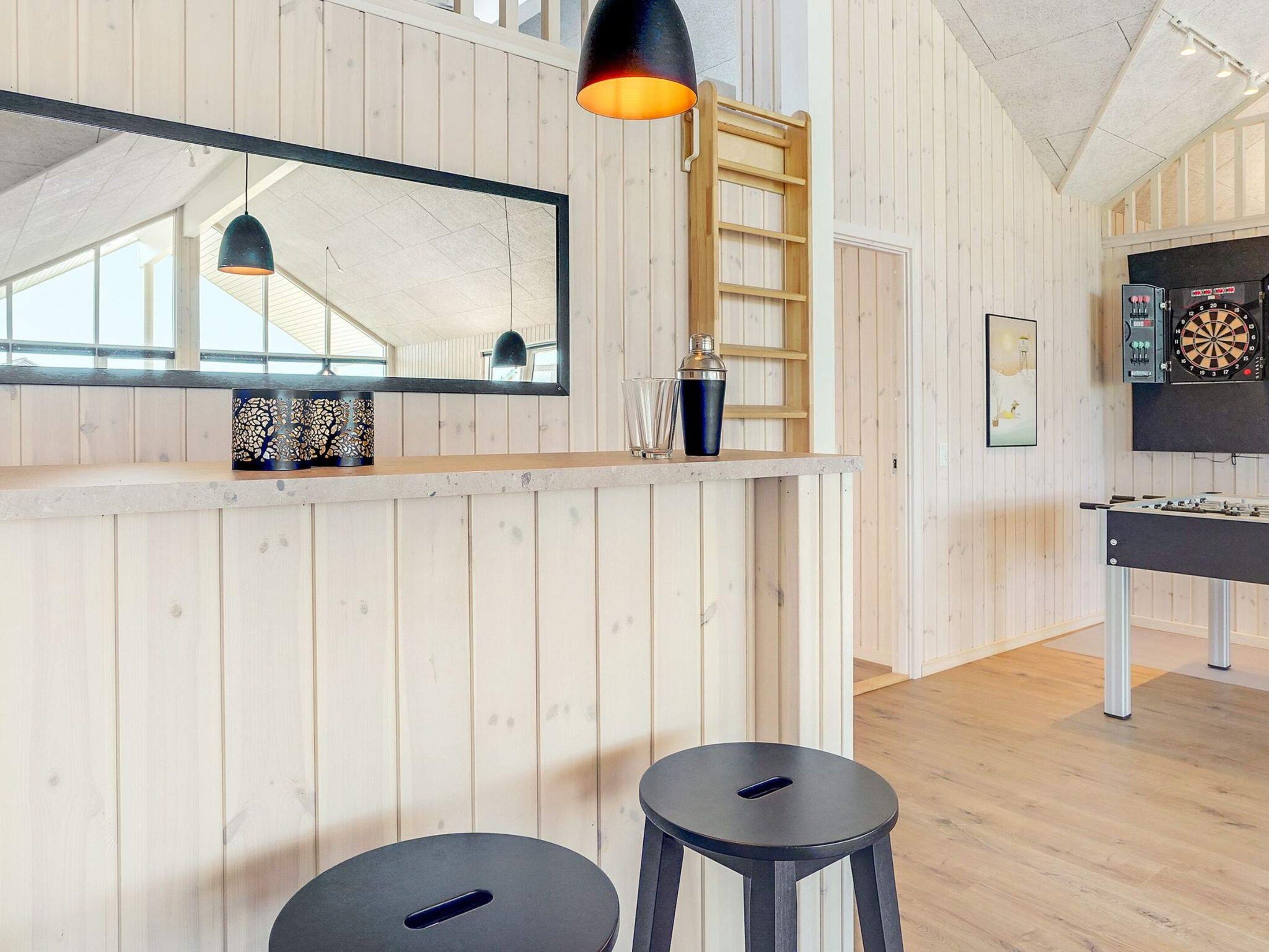 Una habitación con paredes de paneles de madera, un espejo grande, un dardo y una mesa de fútbol de mesa.