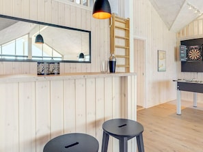 A room with wooden panel walls, a large mirror, a dartboard, and a foosball table.