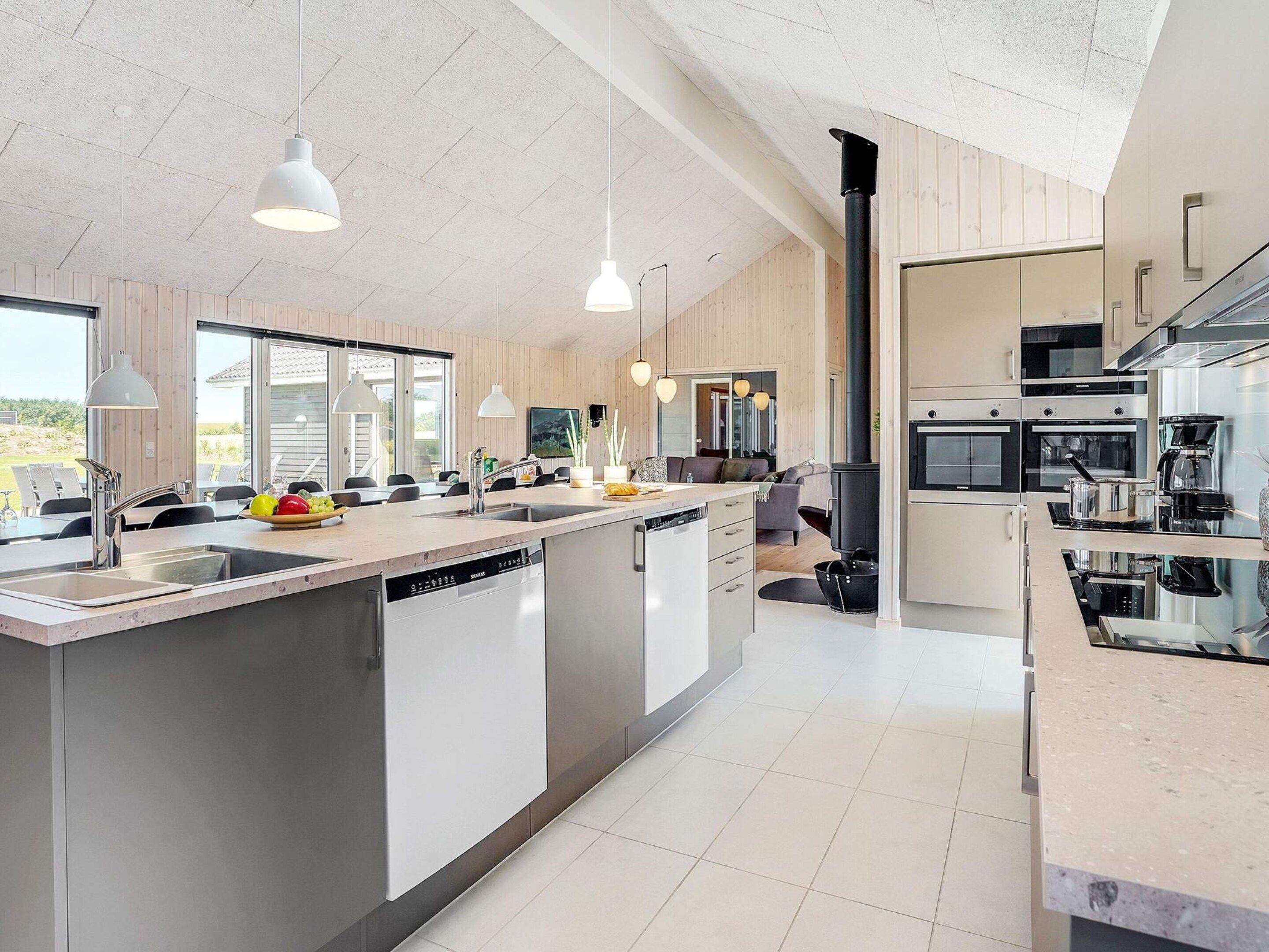 A modern kitchen with a central island, stainless steel appliances, and pendant lighting.