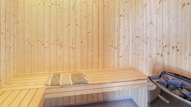 A sauna with a bench, a towel, and a stone heater. - 5 Star Holiday Home in Spottrup (Spøttrup)