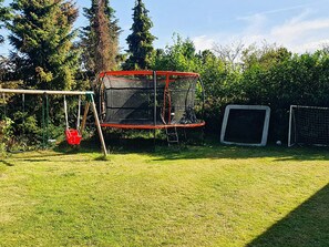 A backyard with a trampoline, a swing set, and a soccer goal. - 6 Person Holiday Home in Hojby (Hojby)