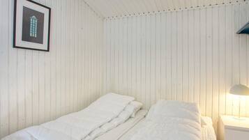 A room with a bed, a nightstand, a framed picture, and a lamp.