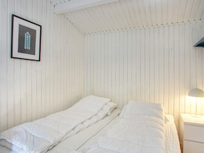 A room with a bed, a nightstand, a framed picture, and a lamp.
