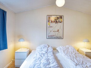 A hotel room with two beds, a poster on the wall, and bedside lamps. - 6 Person Holiday Home in Hojby (Hojby)