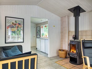 A living room with a sofa, a fireplace, and a framed picture on the wall. - 6 Person Holiday Home in Hojby (Hojby)