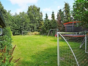 A fenced backyard with a trampoline, a basketball hoop, and a soccer goal. - 6 Person Holiday Home in Hojby (Hojby)