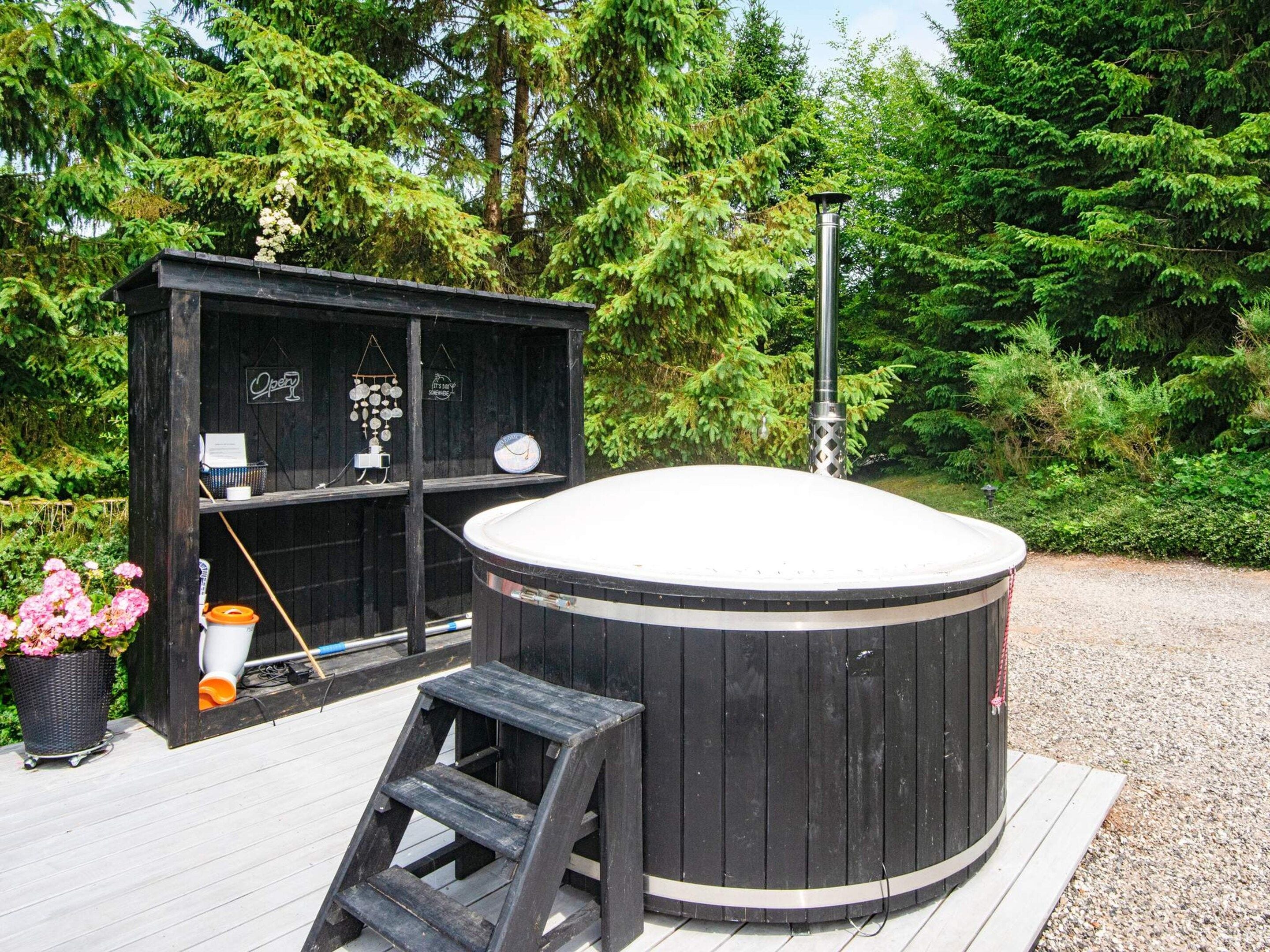 Ein Whirlpool auf einer Holzterrasse mit einer Holzhütte im Hintergrund.