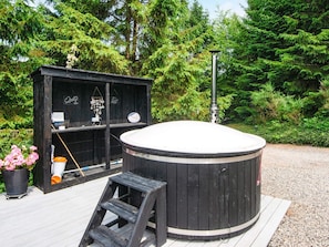 Un jacuzzi en una terraza de madera con una estructura de madera al fondo.