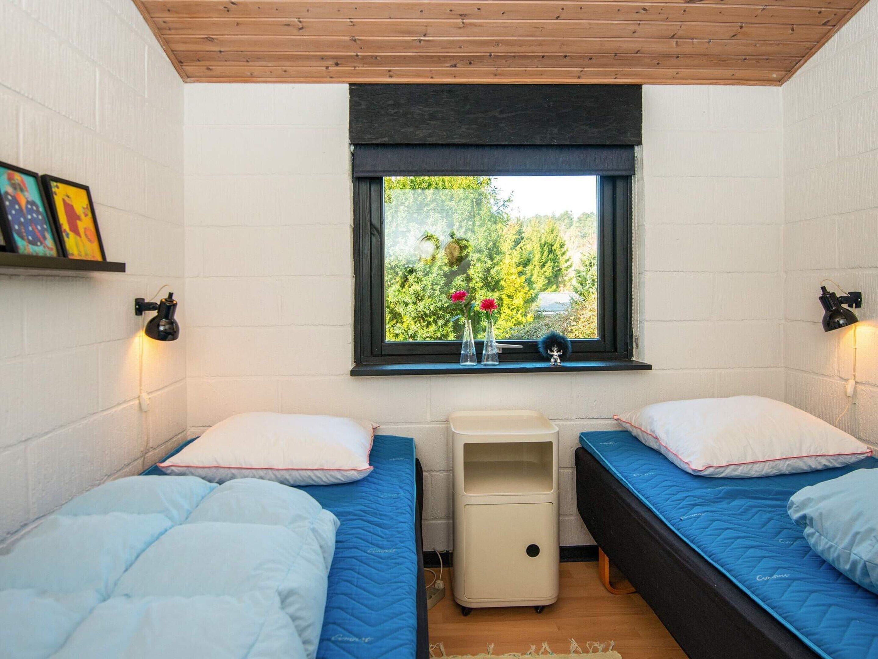 Una habitación con dos camas, una ventana con vistas a zonas verdes y una mesita de noche.