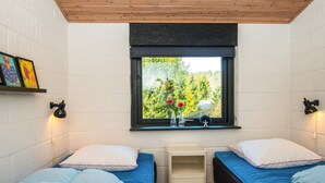 A room with two beds, a window with a view of greenery, and a small bedside table. - 4 Star Holiday Home in Ebeltoft (Ebeltoft)