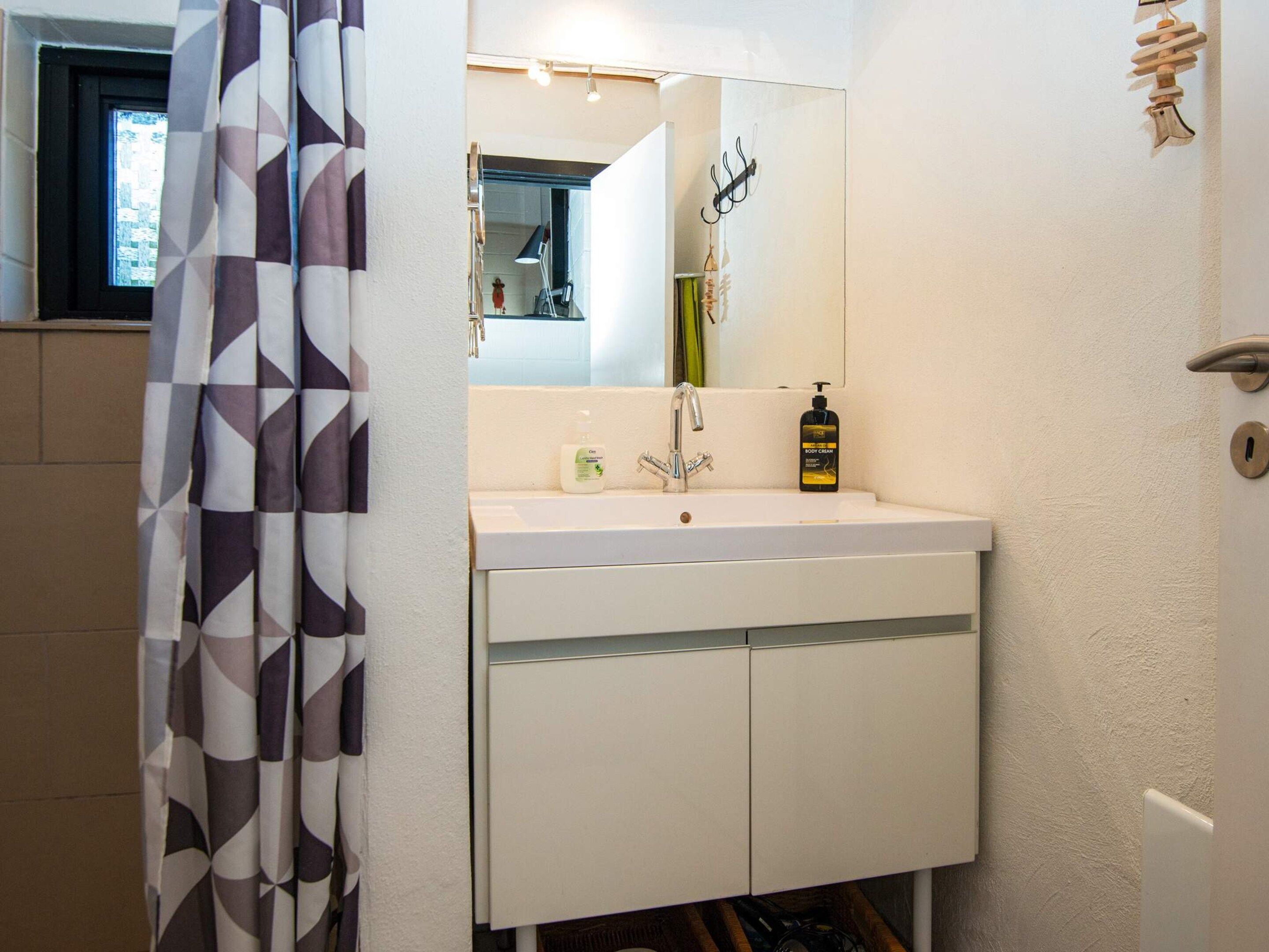 A bathroom with a white sink, a mirror, and a shower curtain with a geometric pattern.