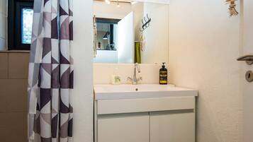 A bathroom with a white sink, a mirror, and a shower curtain with a geometric pattern.